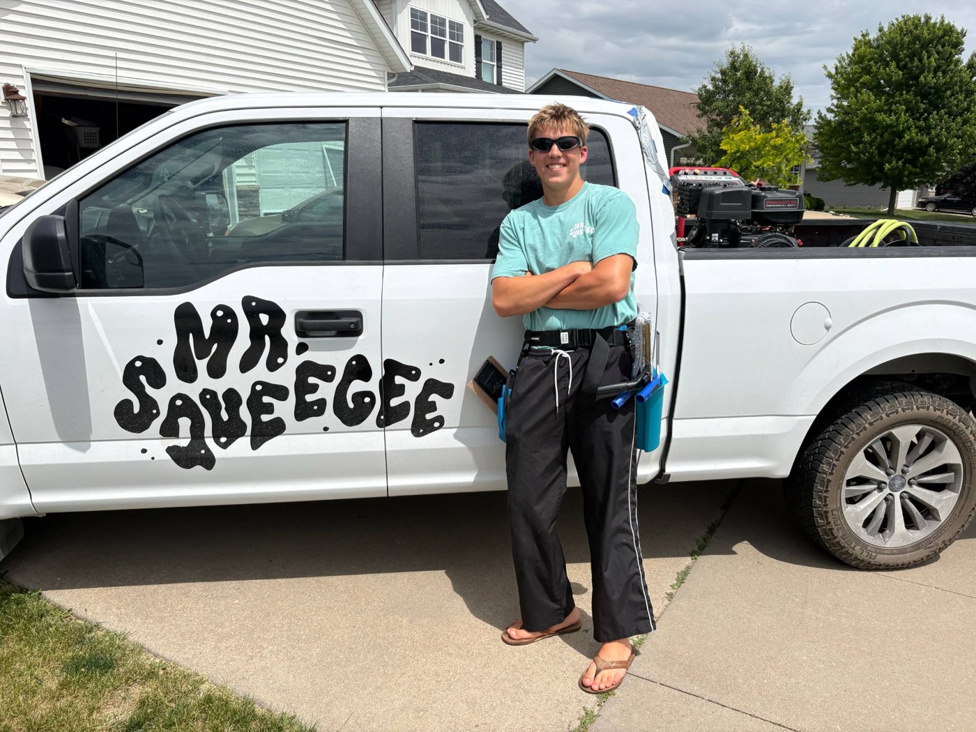 A Mr. Squeegee crew member in his tool belt leaning on the company truck